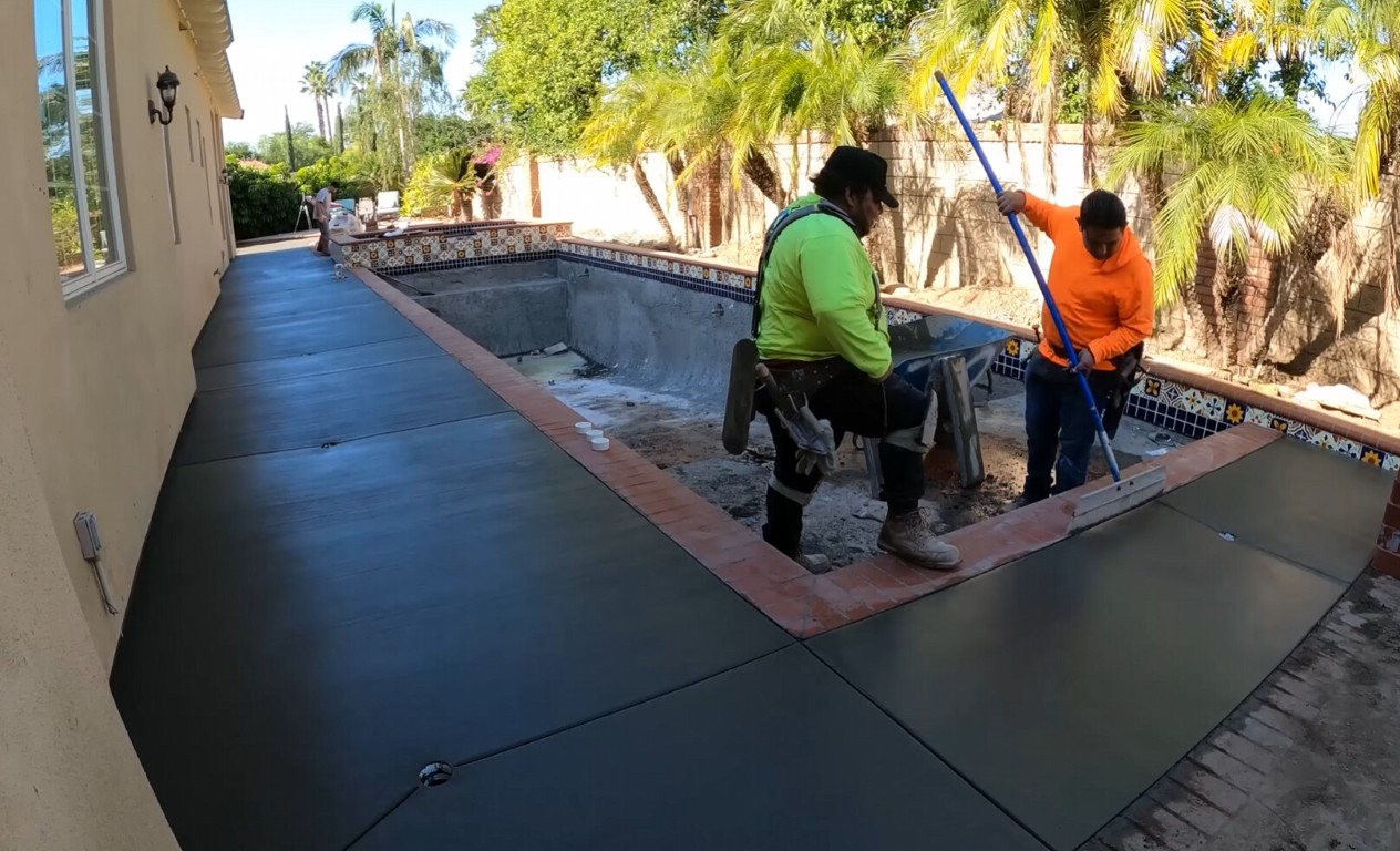 Contractors installing a smooth concrete pool deck around a residential swimming pool in Cupertino, CA